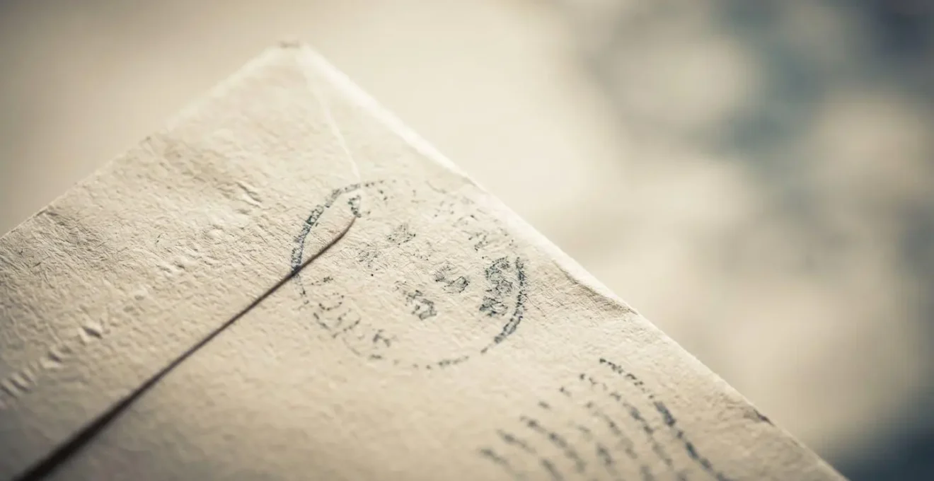 Gros plan tactile d'une enveloppe administrative avec cachet postal visible, symbolisant la preuve de réception d'une offre de crédit immobilier