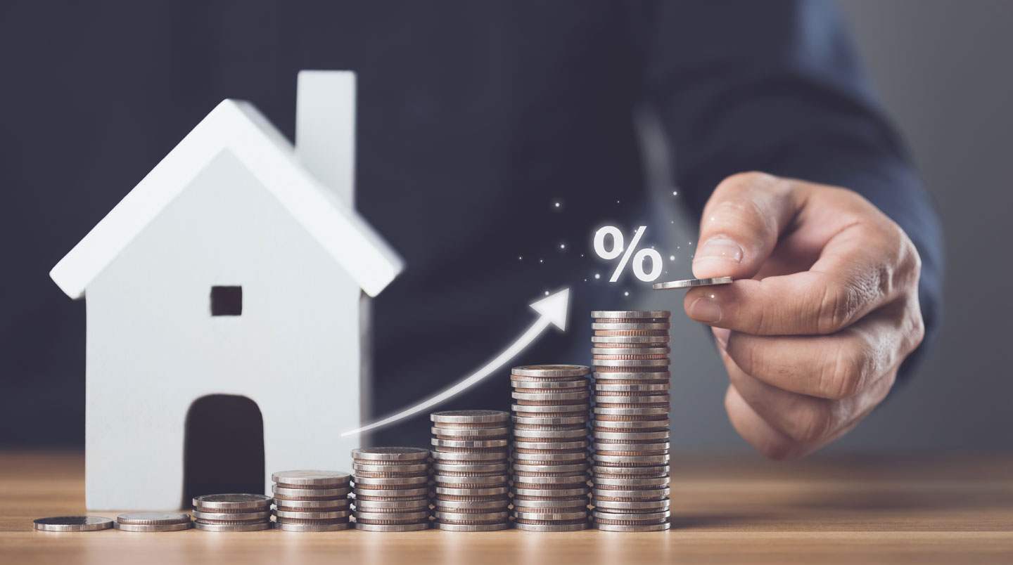 Écran d'ordinateur affichant un tableau d'amortissement de prêt immobilier avec colonnes détaillées en français (Capital, Intérêts, Assurance, Frais, Mensualité), main pointant vers une ligne spécifique, contexte de présentation professionnelle